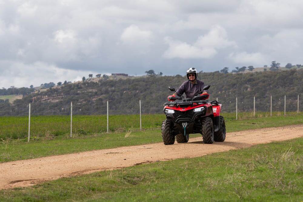 man riding cforce 520L through a field